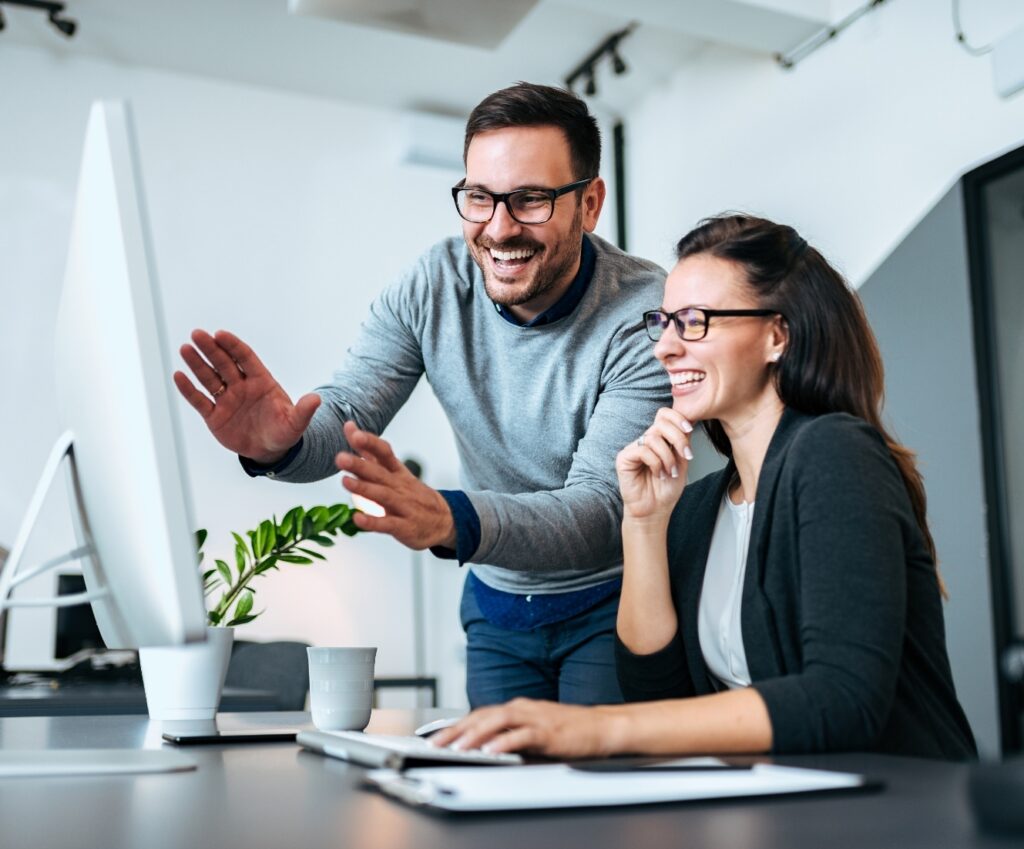 Man and woman excitedly looking at computer together using mortgage technology