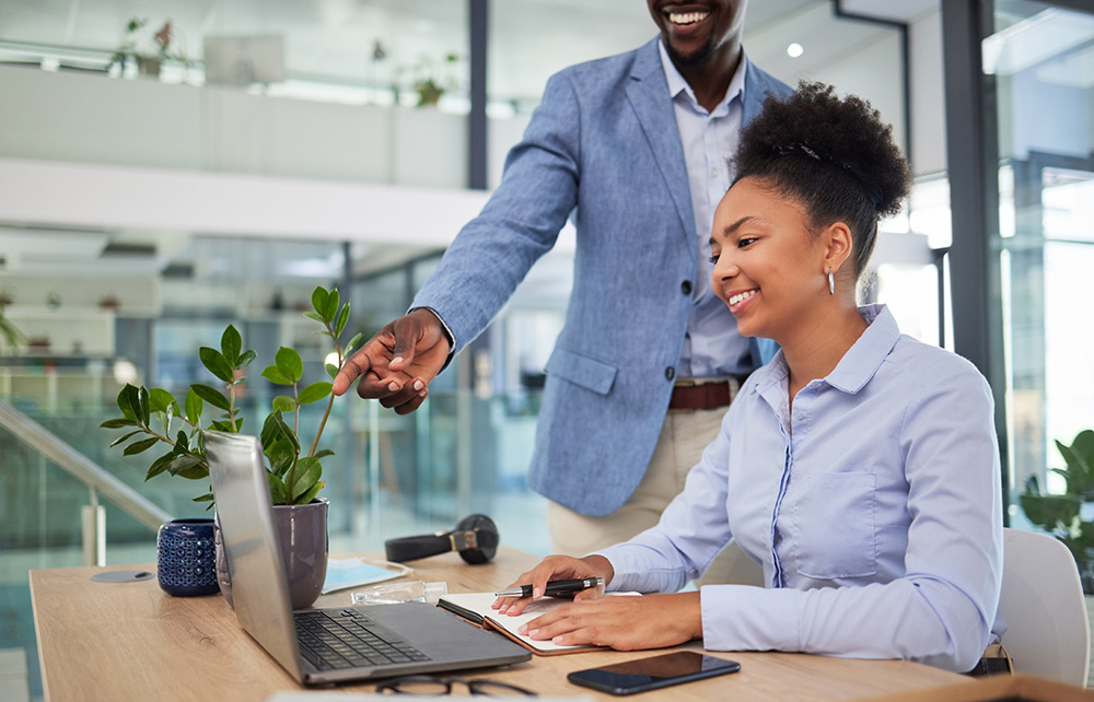Young professional intern working with advisor on a laptop